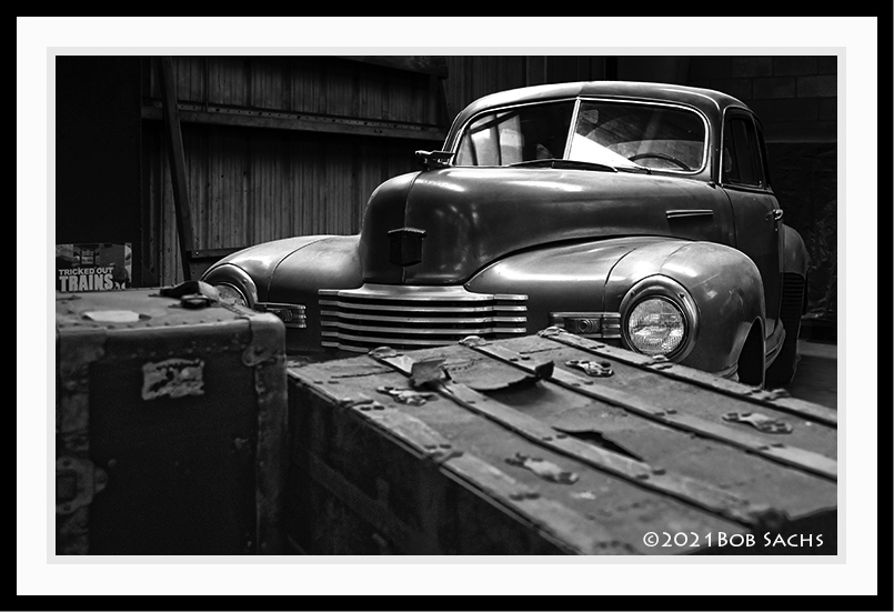 Old car in garage with large trunks.